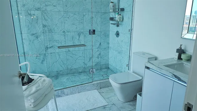 a bathroom with a granite countertop toilet a sink a shower and a mirror