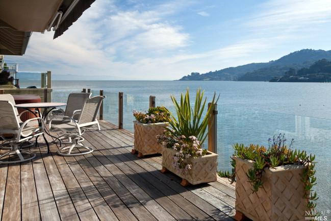 a view of a balcony with chairs and wooden floor