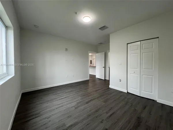 a view of an empty room with wooden floor and a window
