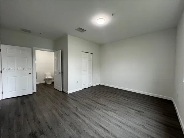 an empty room with wooden floor & windows