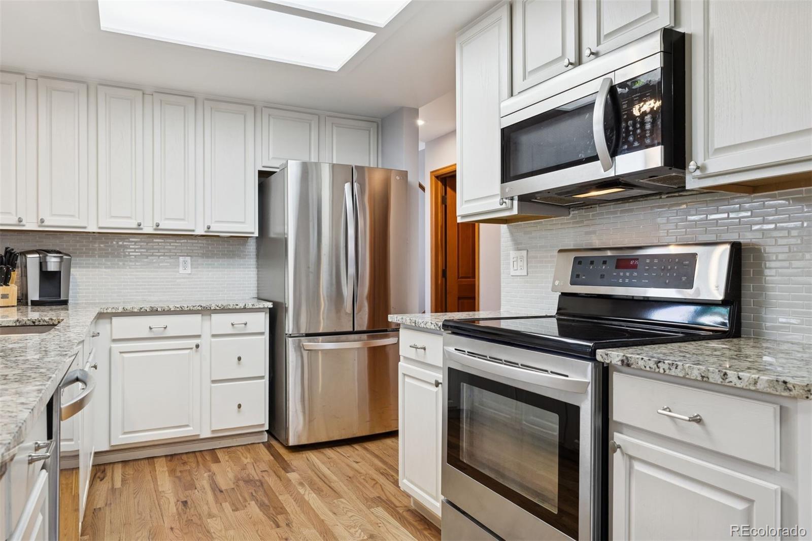 23860 Genesee Village Road Golden, CO 80401 - Photo 14 of 36 a kitchen with granite countertop cabinets stainless steel appliances and wooden floor