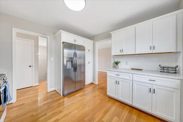 a kitchen with stainless steel appliances granite countertop a refrigerator and white cabinets