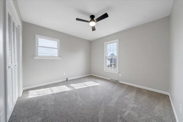 an empty room with windows and ceiling fan