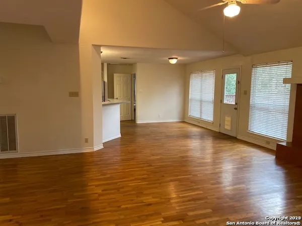 a view of an empty room with window and wooden floor