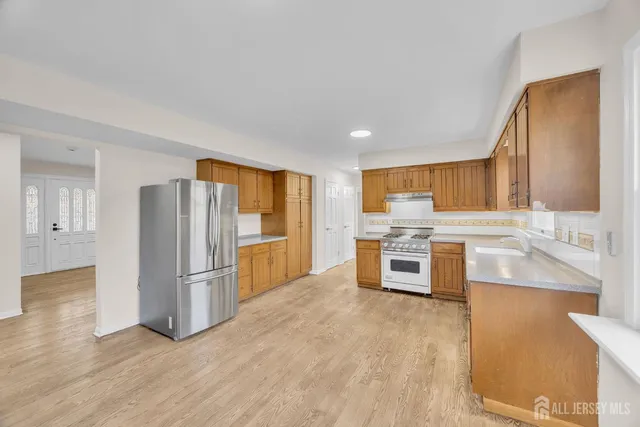 a large kitchen with stainless steel appliances granite countertop a stove a sink and a refrigerator