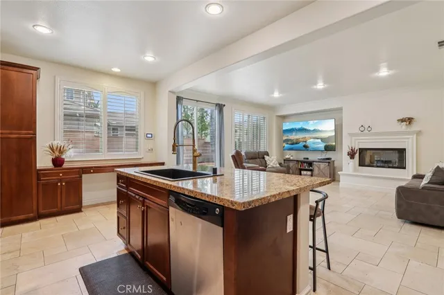 a kitchen with stainless steel appliances granite countertop a stove a sink a refrigerator and couches