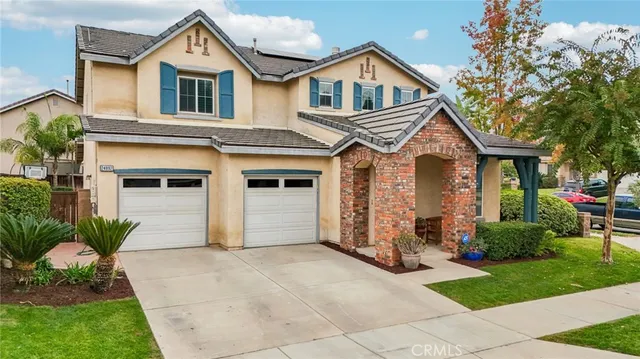 a view of a white house next to a yard with potted plants