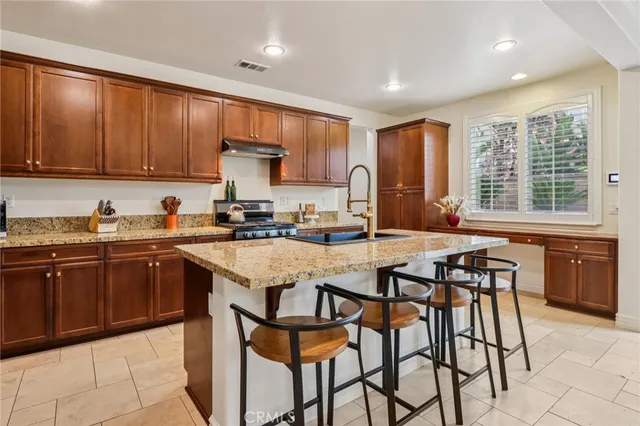 a kitchen with stainless steel appliances granite countertop wooden cabinets a dining table and chairs