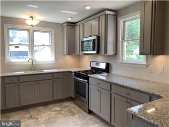 905 Rodman Road Bellefonte, DE 19809 - Photo 8 of 25 a kitchen with stainless steel appliances granite countertop a sink a stove a microwave and wooden cabinets
