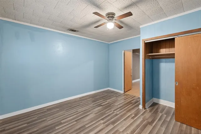 an empty room with wooden floor chandelier fan and windows
