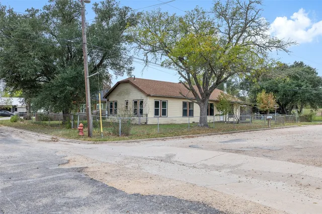 a view of a house with a yard and a large tree