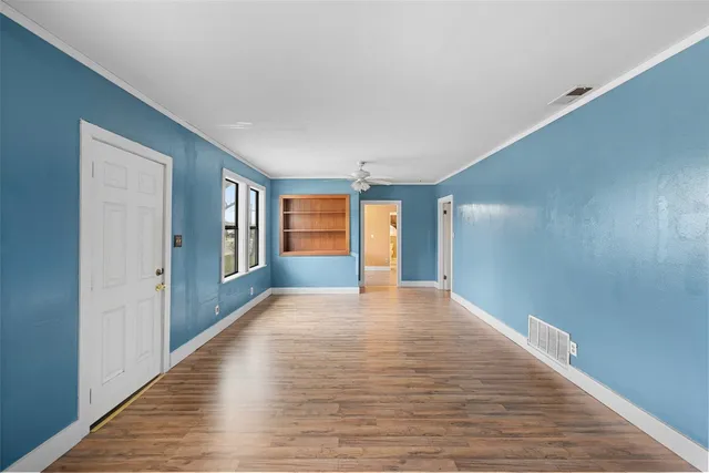 a view of an empty room with window and wooden floor