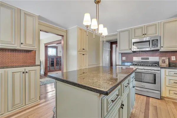 a kitchen with stainless steel appliances granite countertop a refrigerator a stove and white cabinets with wooden floor