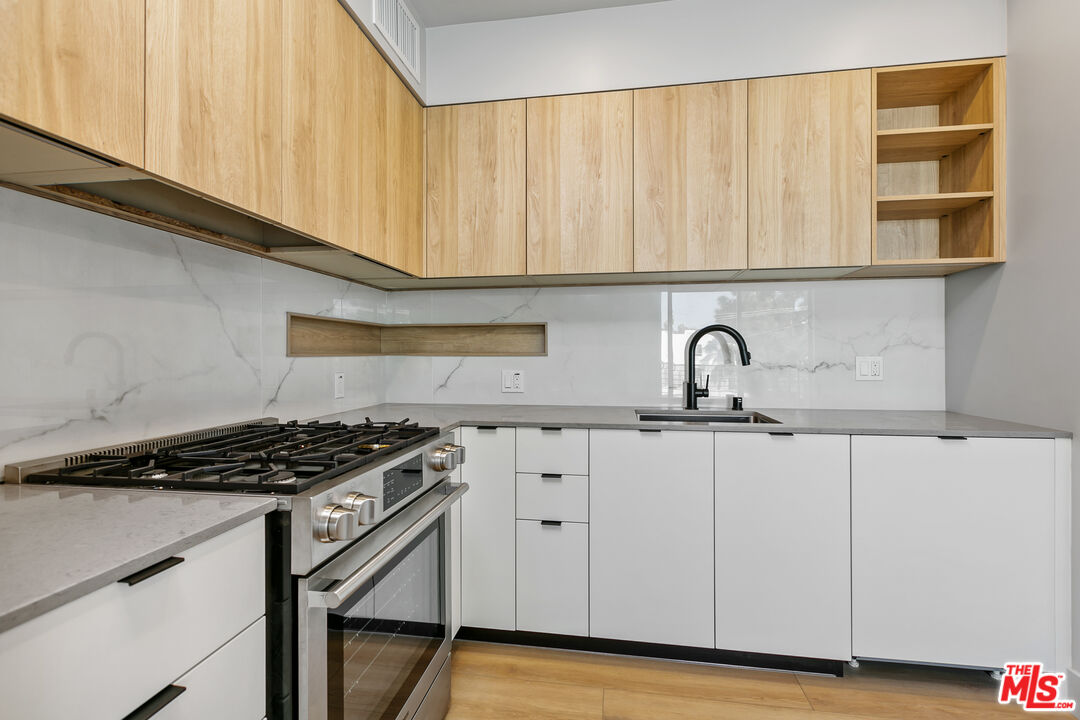 12431 Rochester Avenue, Unit PH7 Los Angeles, CA 90025 - Photo 4 of 23 a kitchen with granite countertop a sink a stove and cabinets