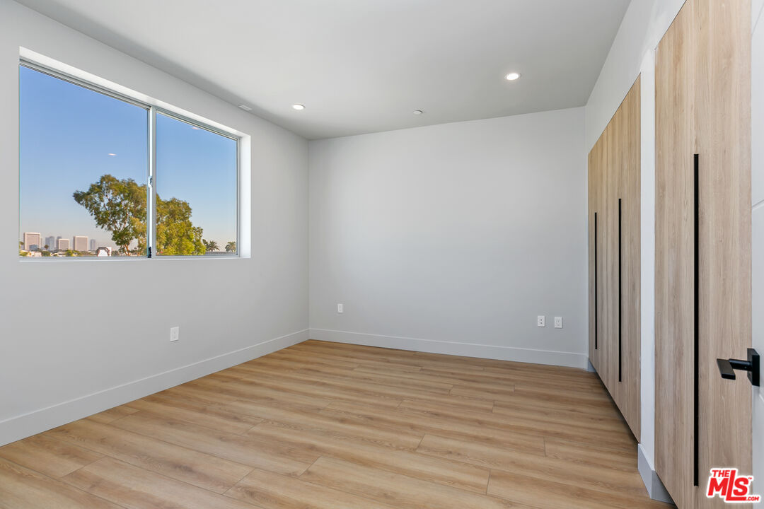 12431 Rochester Avenue, Unit PH7 Los Angeles, CA 90025 - Photo 8 of 23 wooden floor in an empty room with a window