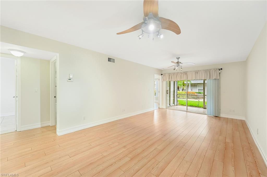 a view of an empty room with wooden floor ceiling fan