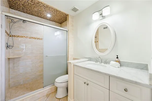 a bathroom with a granite countertop sink mirror vanity and toilet