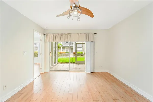 a view of an empty room with a window and wooden floor