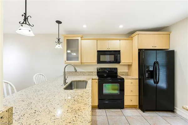 a kitchen with stainless steel appliances kitchen island granite countertop a refrigerator a stove and a sink