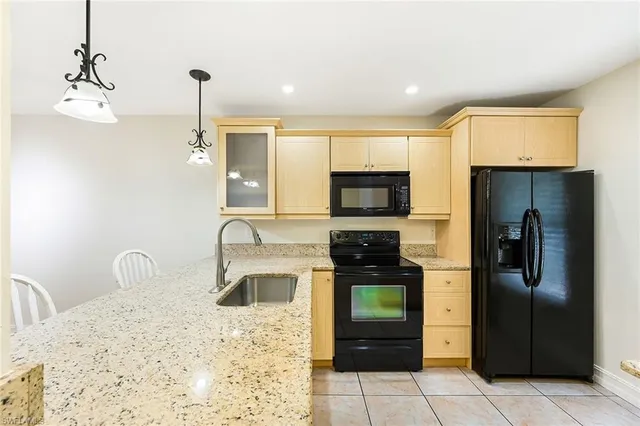 a kitchen with stainless steel appliances kitchen island granite countertop a refrigerator a stove and a sink