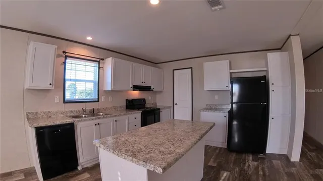 a kitchen with granite countertop kitchen island stainless steel appliances a refrigerator sink stove microwave and cabinets