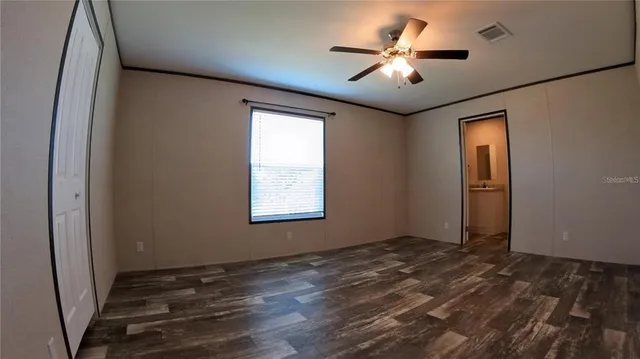 an empty room with windows and fan