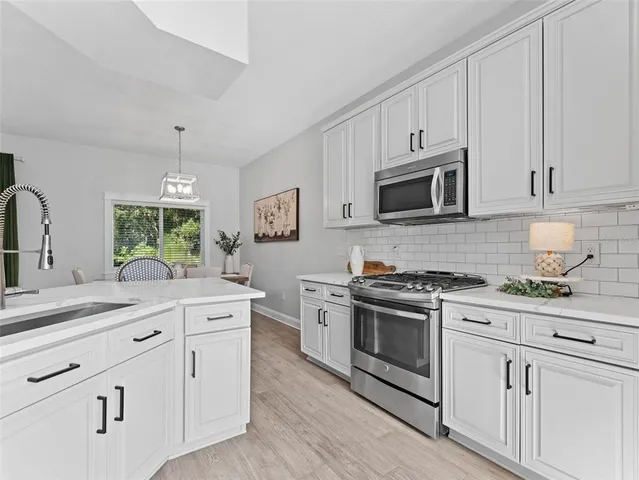 a kitchen with white cabinets stainless steel appliances and sink