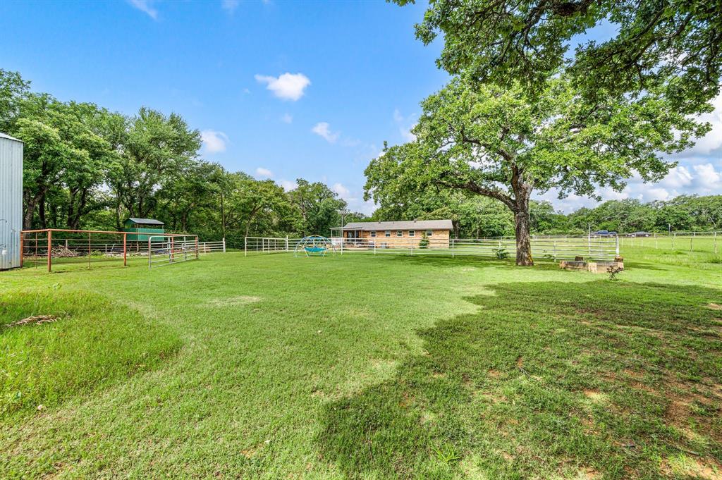 3900 Moseley Road Cross Roads, TX 76227 - Photo 29 of 36 Expansive grassy area with mature trees and a distant single-story structure