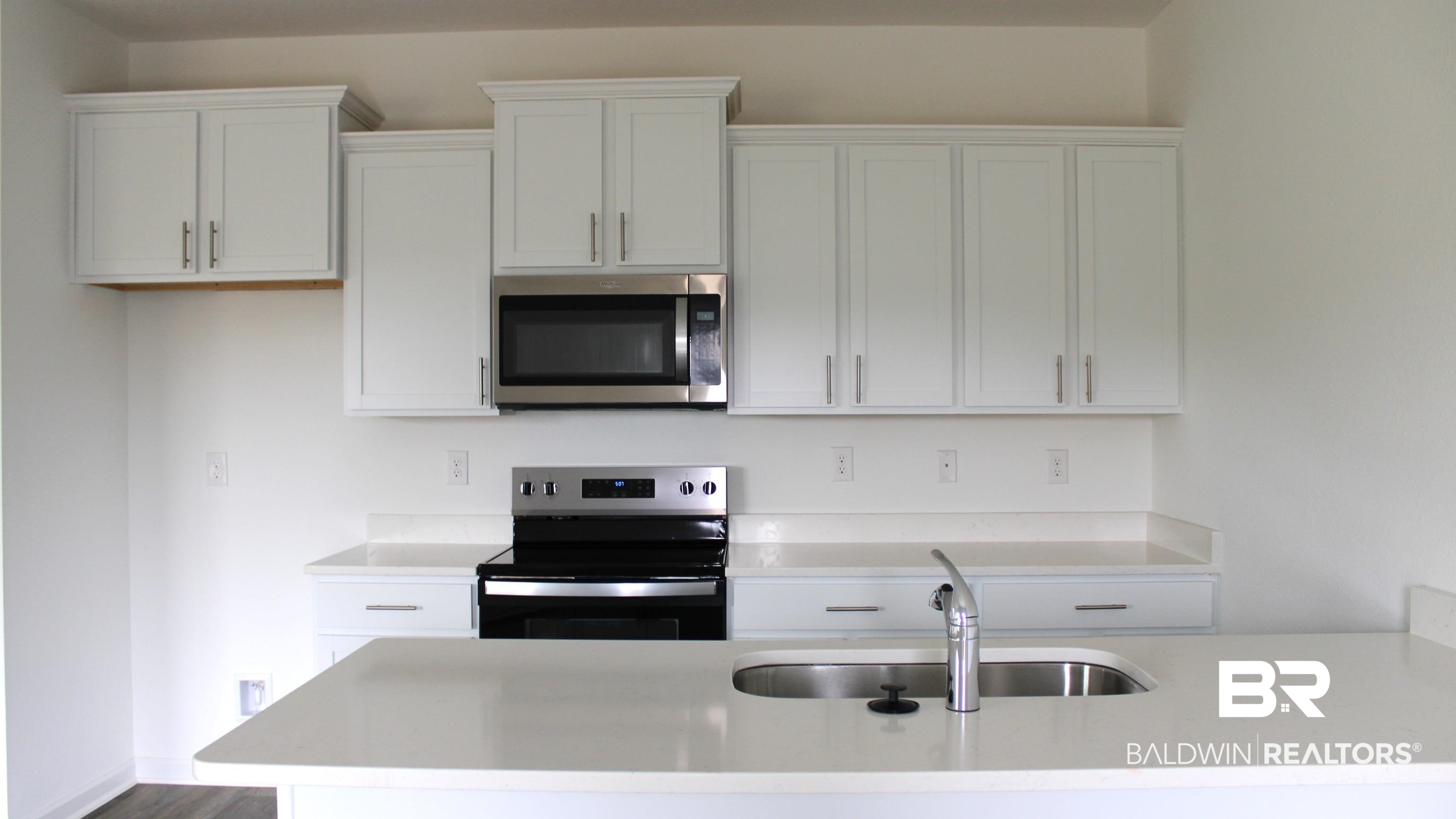 652 Overland Drive Fairhope, AL 36532 - Photo 3 of 30 Kitchen with a sink, light countertops, electric stove, stainless steel microwave, and white cabinetry