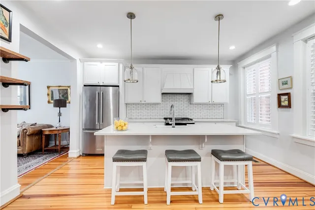 a kitchen with stainless steel appliances kitchen island granite countertop a table chairs in it and wooden floors