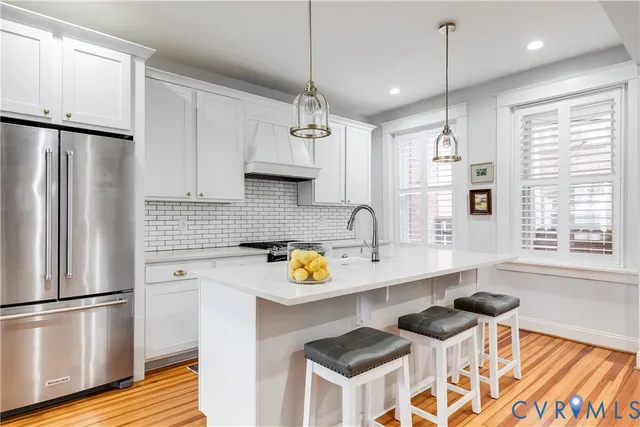 a kitchen with stainless steel appliances a sink a stove a refrigerator a center island and a window