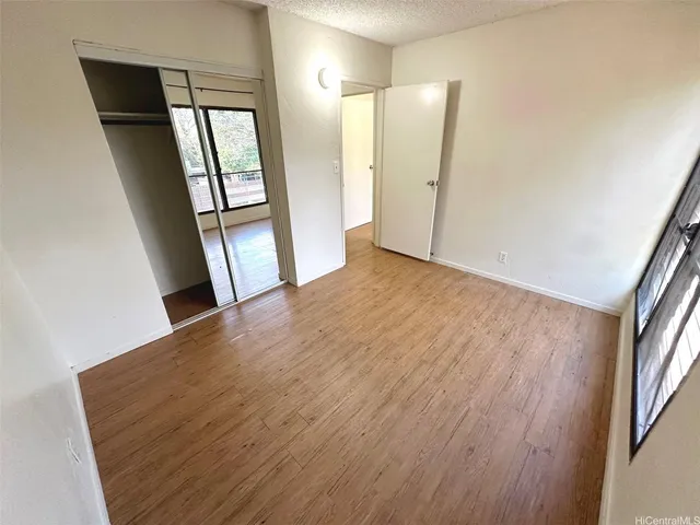 a view of empty room with wooden floor and staircase