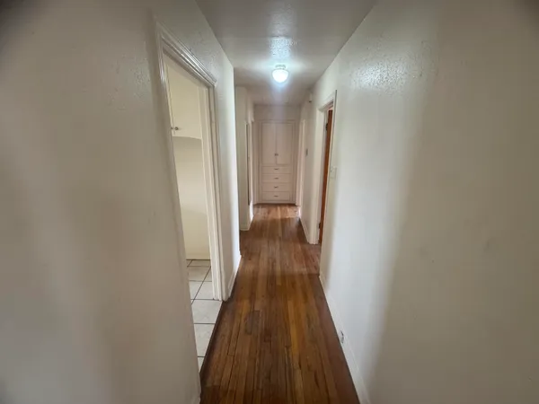 a view of a hallway with wooden floor and a bathroom