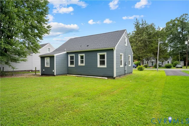 a backyard of a house with plants and large tree