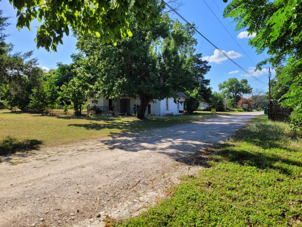 909 Ivan Road Waco, TX 76706 - Photo 3 of 10 White residential structure with a covered porch, set on a grassy lot with mature trees