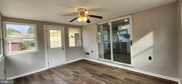 an empty room with wooden floor fan and windows