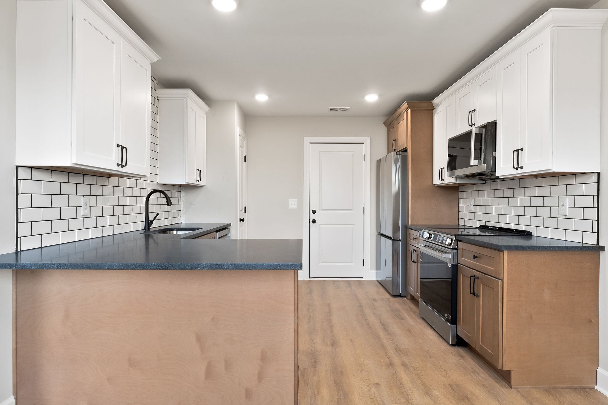 3535 Keltonburg Road Smithville, TN 37166 - Photo 11 of 37 a large kitchen with stainless steel appliances granite countertop a stove a sink a refrigerator and white cabinets with wooden floor