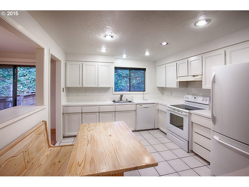 31 Southwest Taylors Ferry Road Portland, OR 97219 - Photo 9 of 23 a kitchen with granite countertop a stove a sink dishwasher a refrigerator and white cabinets with wooden floor