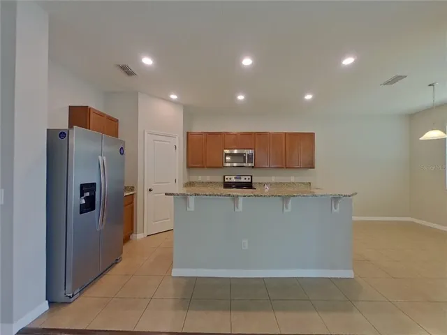 a large kitchen with stainless steel appliances a refrigerator and a stove top oven