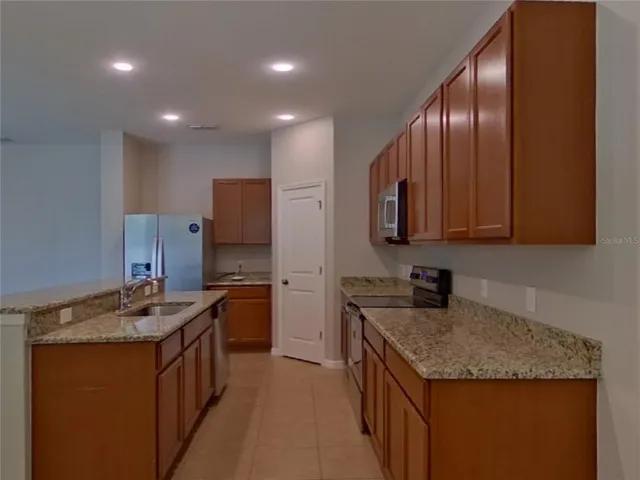 a kitchen with granite countertop stainless steel appliances a sink stove and cabinets