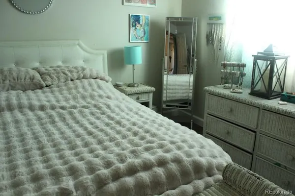 a bed sitting in a bedroom next to a window with chair