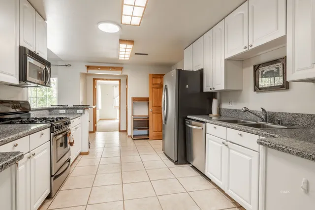 a large kitchen with stainless steel appliances granite countertop a stove top oven a sink dishwasher and a refrigerator