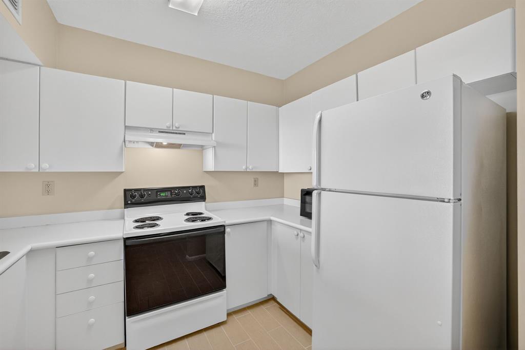 3020 Northeast 32nd Avenue, Unit 819 Fort Lauderdale, FL 33308 - Photo 11 of 68 a kitchen with a stove a refrigerator and white cabinets