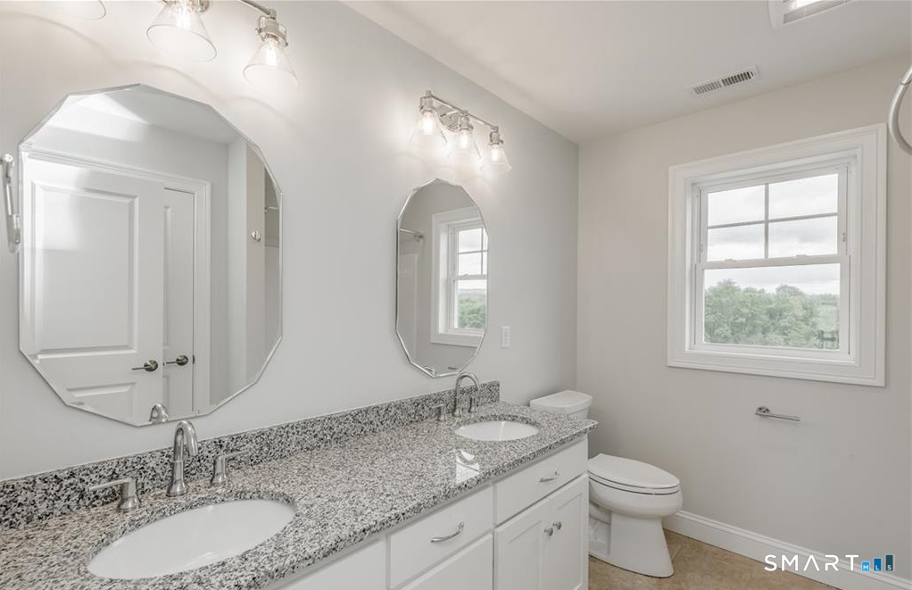 106 Rock Ridge Road Manchester, CT 06040 - Photo 18 of 19 a bathroom with double vanity sinks a toilet a mirror and a window