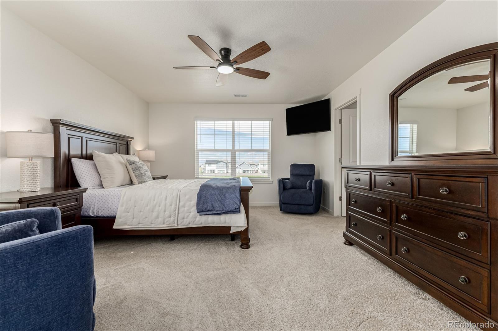773 Allium Street Watkins, CO 80137 - Photo 18 of 46 a bedroom with a bed and dresser with mirror