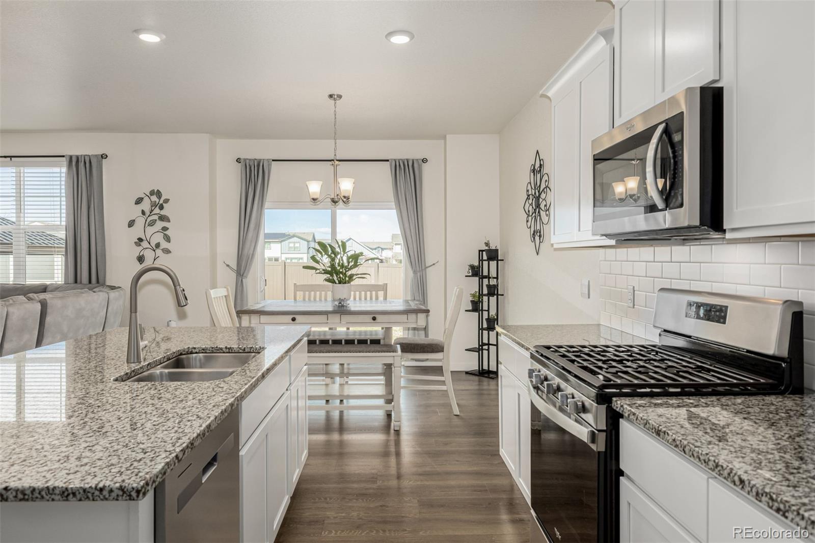 773 Allium Street Watkins, CO 80137 - Photo 3 of 46 a kitchen with stainless steel appliances granite countertop a stove a sink and a microwave