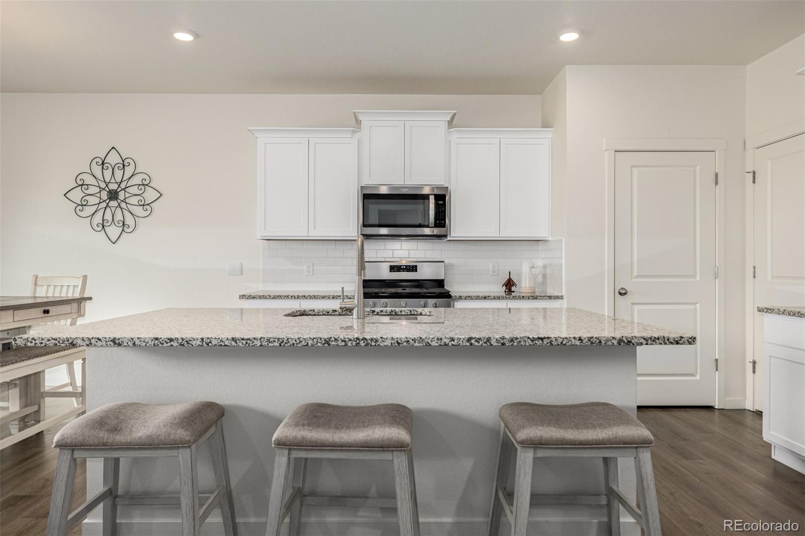 773 Allium Street Watkins, CO 80137 - Photo 4 of 46 a kitchen with granite countertop a sink and white cabinets