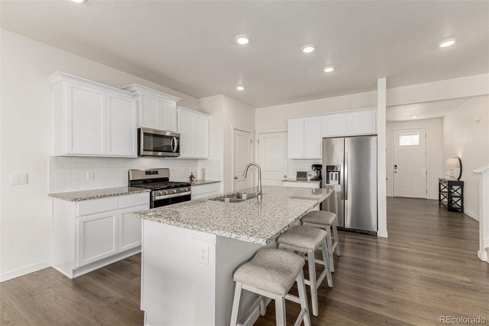 773 Allium Street Watkins, CO 80137 - Photo 5 of 46 a kitchen with stainless steel appliances granite countertop a refrigerator a stove microwave and cabinets