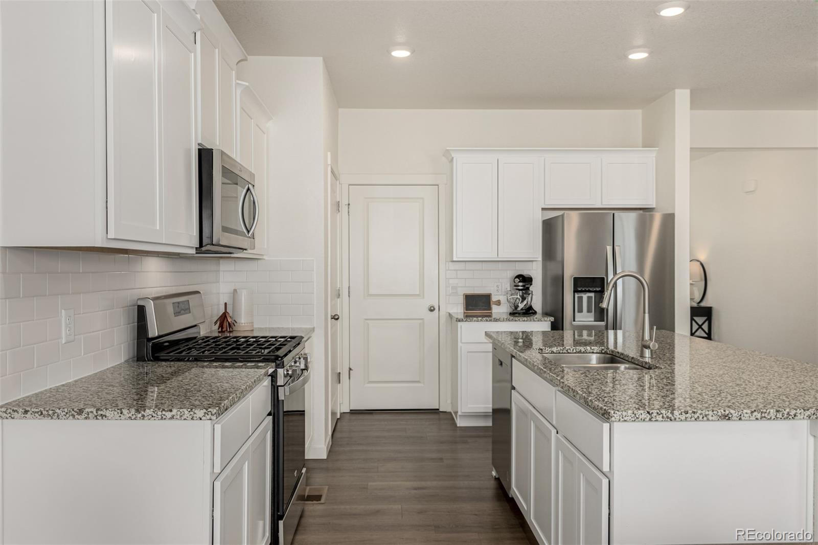 773 Allium Street Watkins, CO 80137 - Photo 6 of 46 a kitchen with granite countertop a sink stove and refrigerator