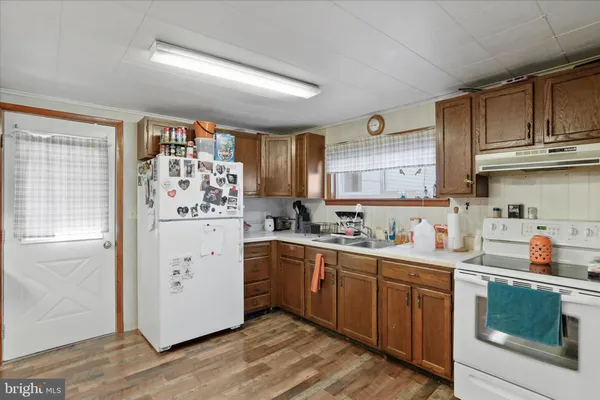 a kitchen with a sink a refrigerator and wooden floor